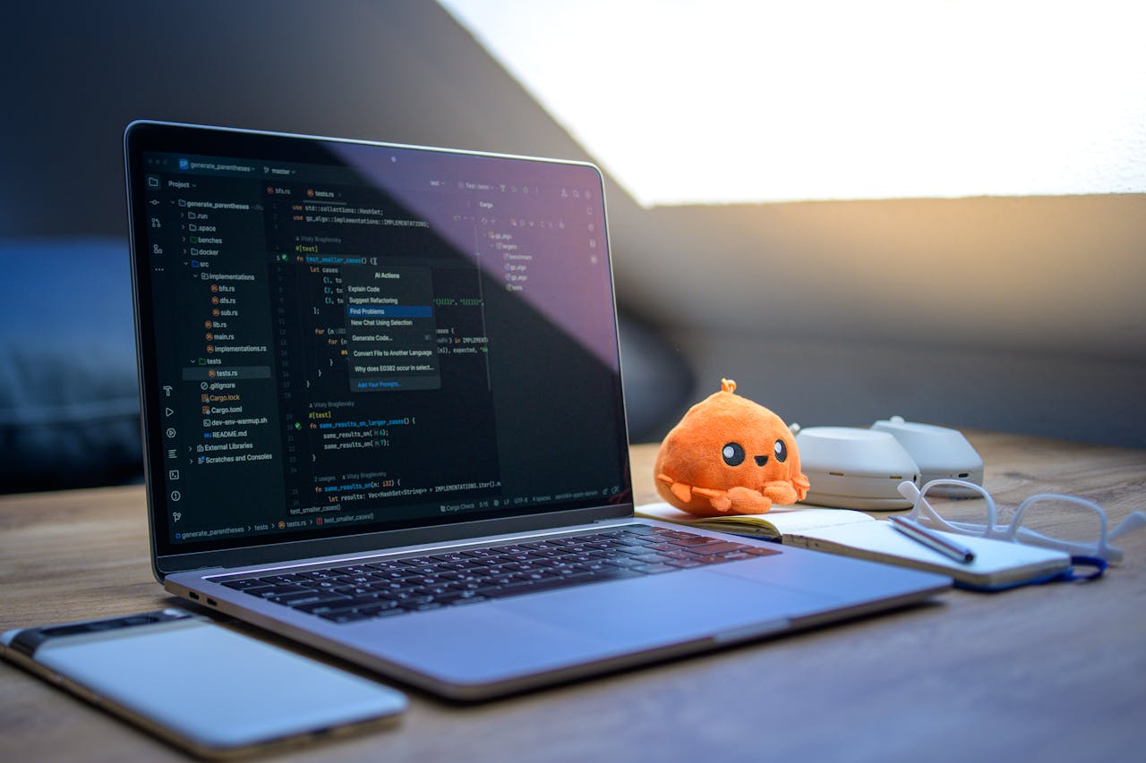 client-satisfaction-img A cozy workspace featuring a laptop displaying code, a smartphone, and a cute orange plush toy on the desk.
