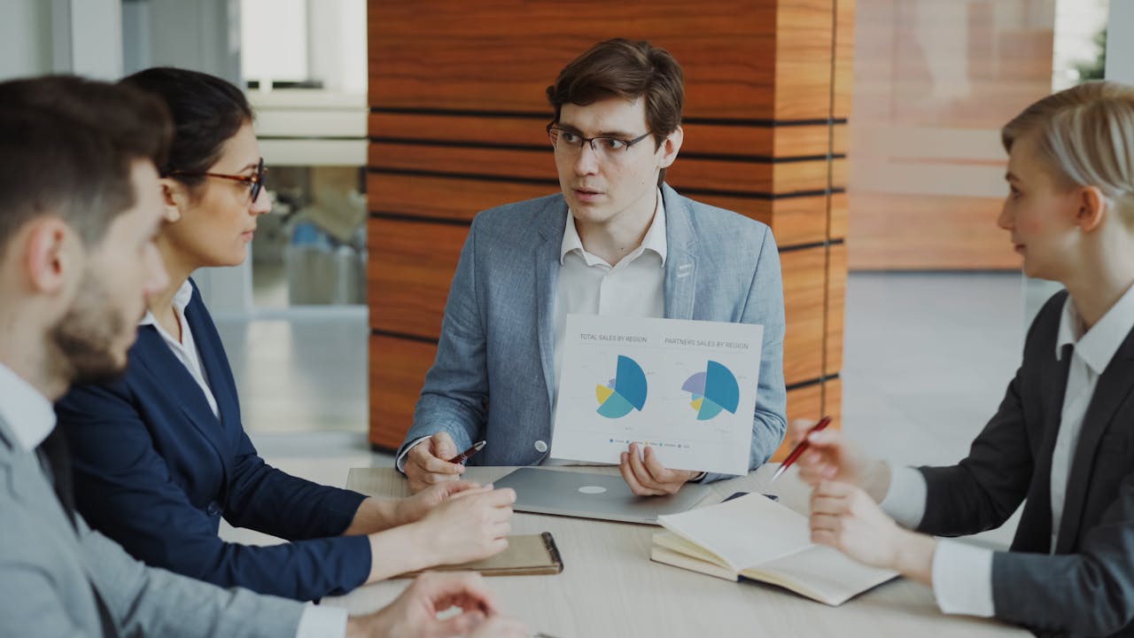 awards-img A team engaged in a business meeting discussing charts and strategies in an office.